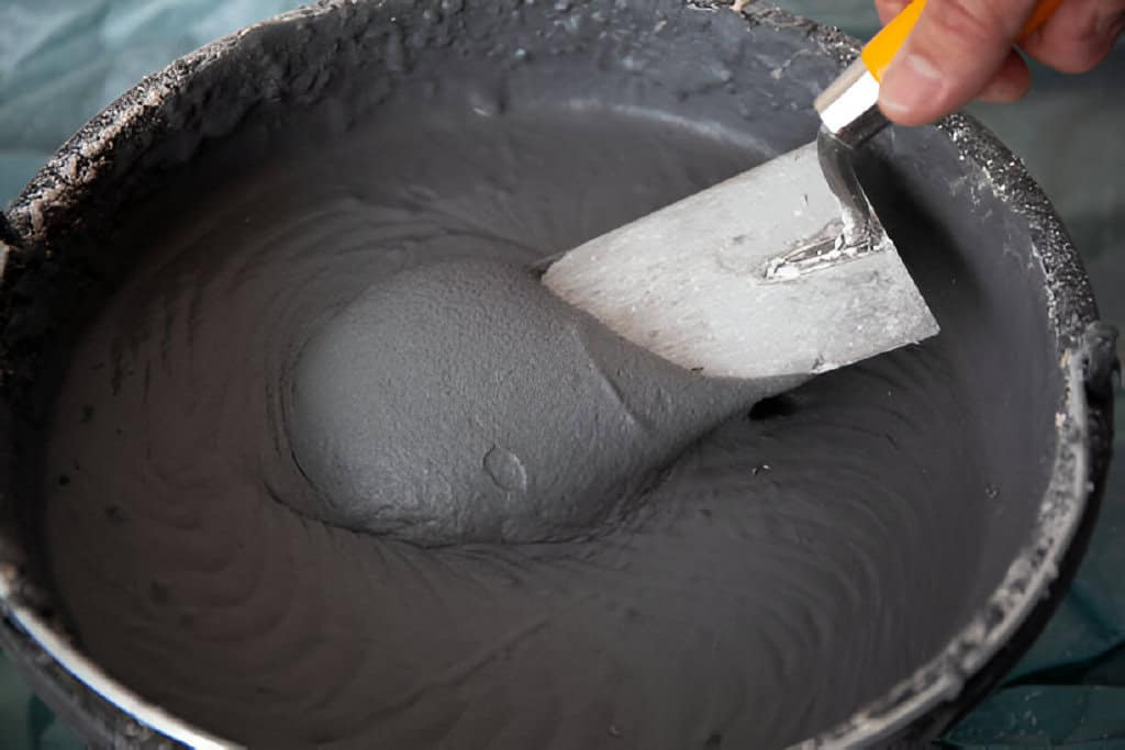 a trowel in a bucket with plaster cement